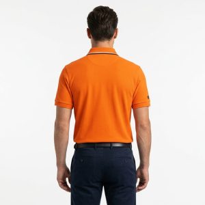 Man wearing a premium men's vibrant orange polo shirt with bold black and white striped sleeve cuffs