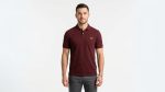 Man wearing a premium men's burgundy maroon polo shirt with a gold embroidered laurel wreath logo on the chest