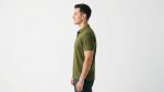 Man wearing a premium men's olive green polo shirt featuring a contrast chest pocket with a topographic map design and flap button closure
